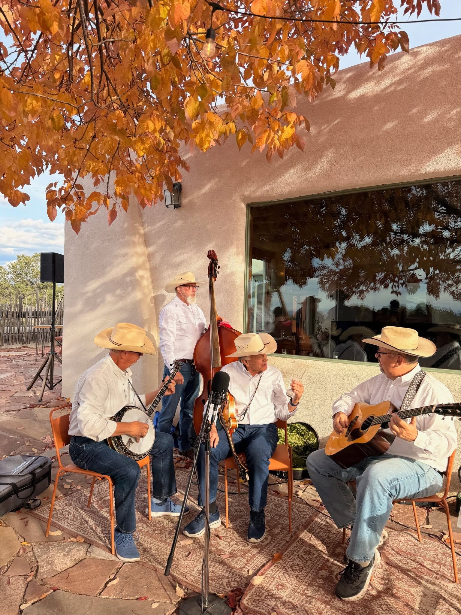 The Santa Fe Grass four-piece bluegrass band performing outdoors on an adobe patio at a New Mexico wedding